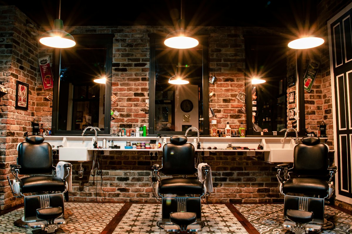 Interior de barbearia com cadeiras de couro e parede de tijolos