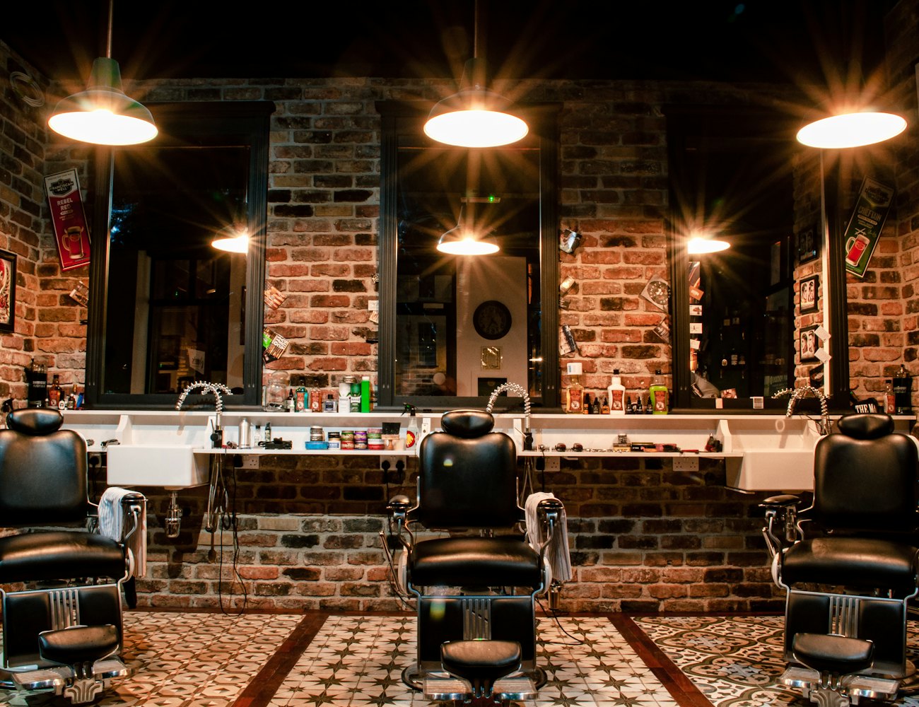 Interior de barbearia com cadeiras de couro e parede de tijolos