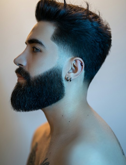 Homem de perfil com barba cheia e degradê