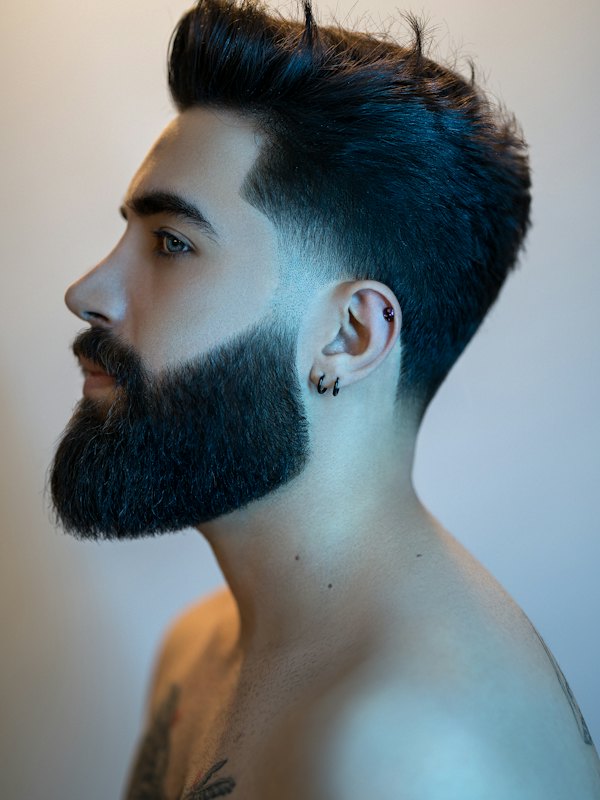 Homem de perfil com barba cheia e degradê