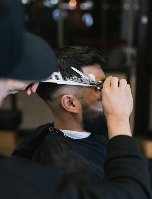 Barbeiro cortando cabelo com tesoura e pente