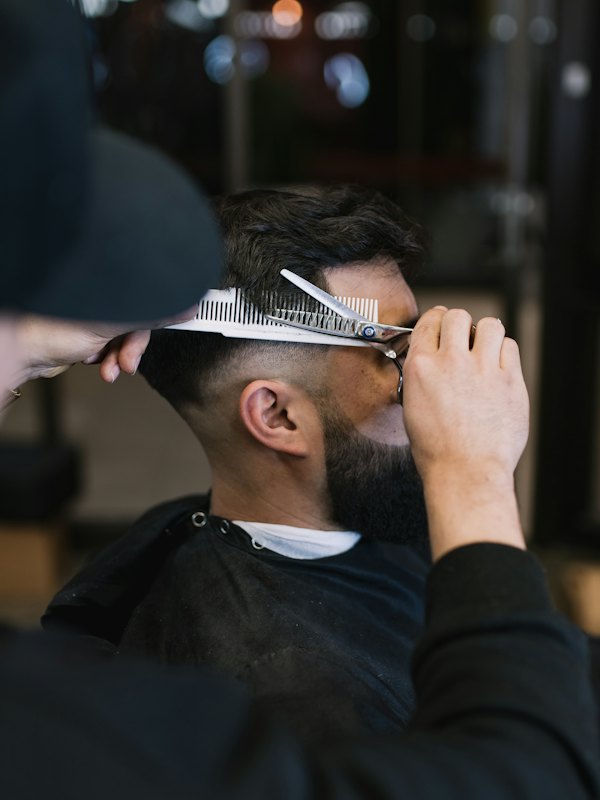 Barbeiro cortando cabelo com tesoura e pente
